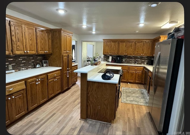 kitchen with decorative backsplash, stainless steel fridge, a center island, and light hardwood / wood-style flooring