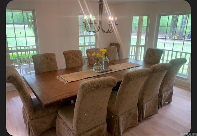 dining area with light wood-type flooring and a notable chandelier