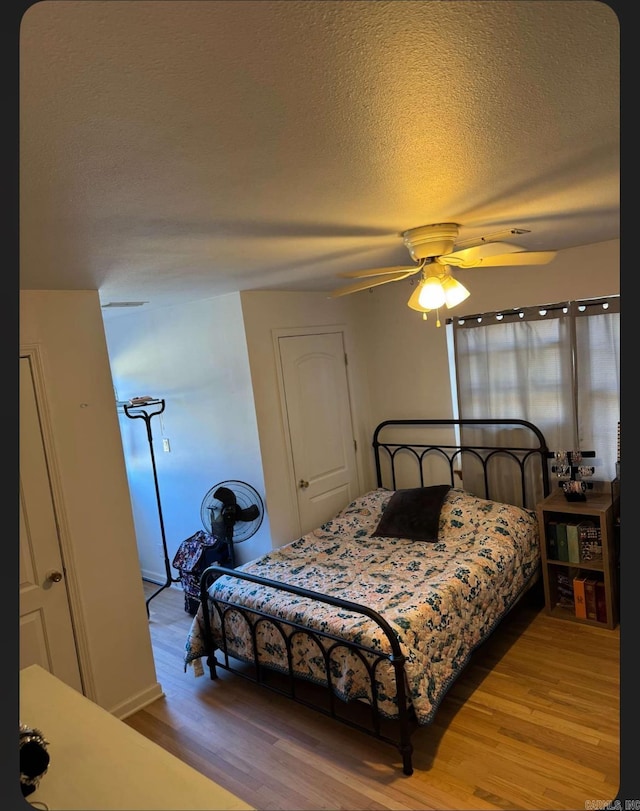 bedroom with hardwood / wood-style floors, a textured ceiling, and ceiling fan