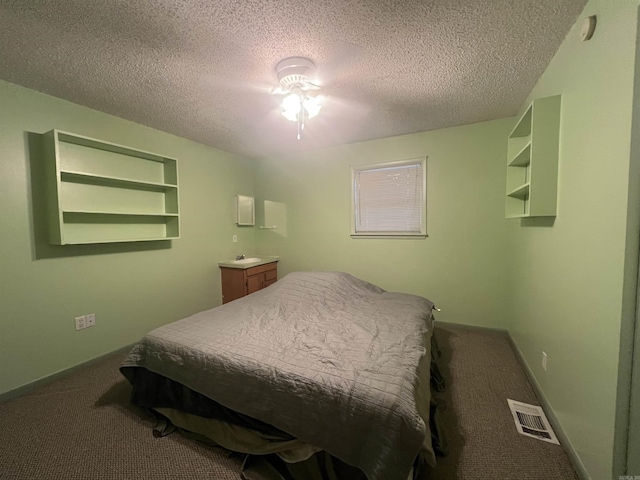 carpeted bedroom featuring ceiling fan and a textured ceiling