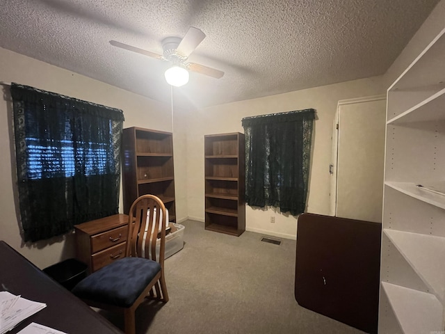 interior space featuring a textured ceiling, ceiling fan, and light colored carpet