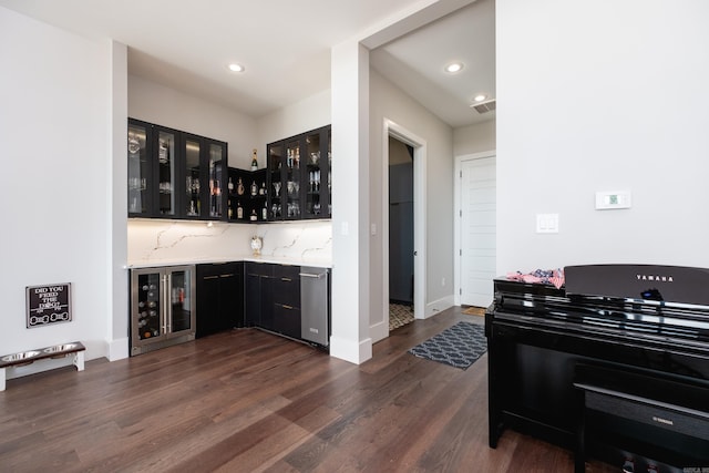 bar with decorative backsplash, light stone counters, beverage cooler, dishwasher, and dark hardwood / wood-style floors