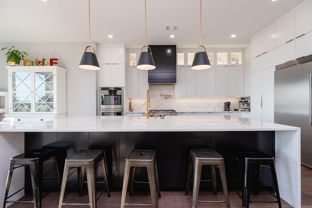 kitchen with a kitchen breakfast bar, white cabinetry, hanging light fixtures, and appliances with stainless steel finishes