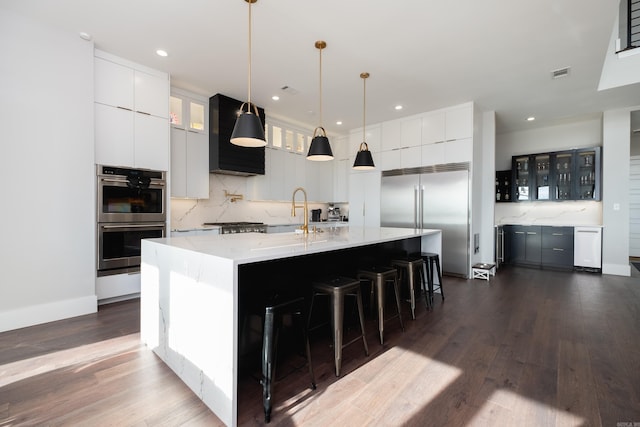 kitchen featuring sink, stainless steel appliances, dark wood-type flooring, pendant lighting, and a spacious island