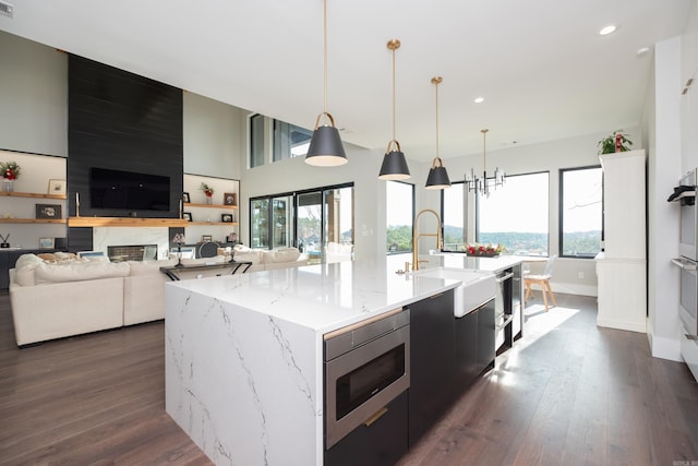 kitchen featuring decorative light fixtures, a kitchen island with sink, and a wealth of natural light