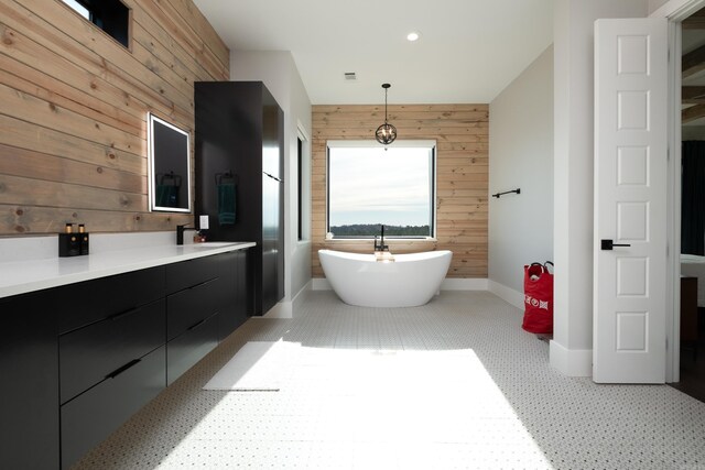 bathroom featuring vanity, a tub to relax in, and wooden walls