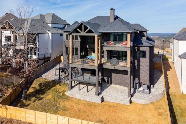 rear view of house with a patio, a balcony, and a lawn