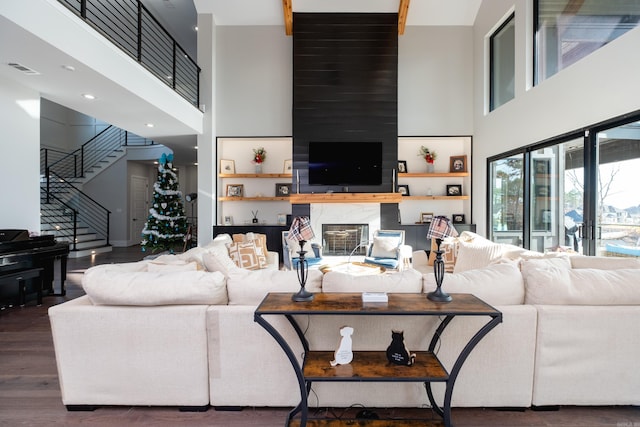 living room featuring wood-type flooring, a fireplace, and a high ceiling