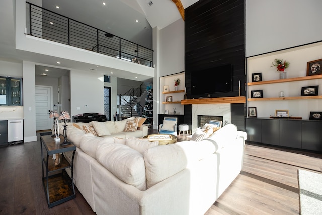 living room featuring hardwood / wood-style floors, a towering ceiling, and a fireplace