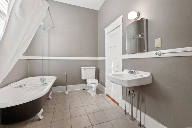 bathroom featuring tile patterned flooring, a bathtub, toilet, and sink