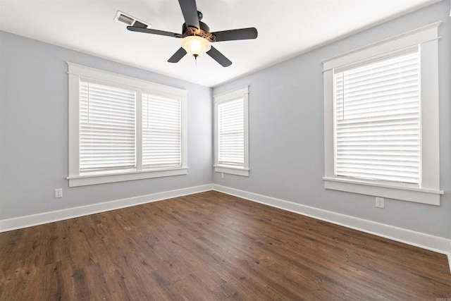 empty room with a wealth of natural light, dark hardwood / wood-style flooring, and ceiling fan