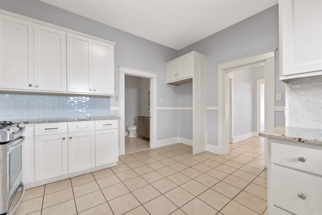 kitchen with white cabinets, decorative backsplash, and stainless steel range oven