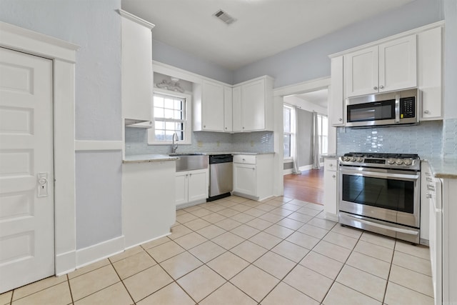 kitchen featuring white cabinetry, a wealth of natural light, sink, and appliances with stainless steel finishes