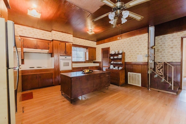 kitchen with a kitchen island, white appliances, and light hardwood / wood-style flooring