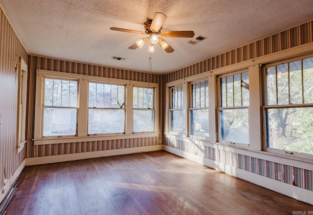 unfurnished sunroom with ceiling fan and plenty of natural light