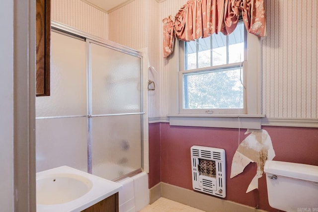 full bathroom featuring vanity, heating unit, toilet, and enclosed tub / shower combo