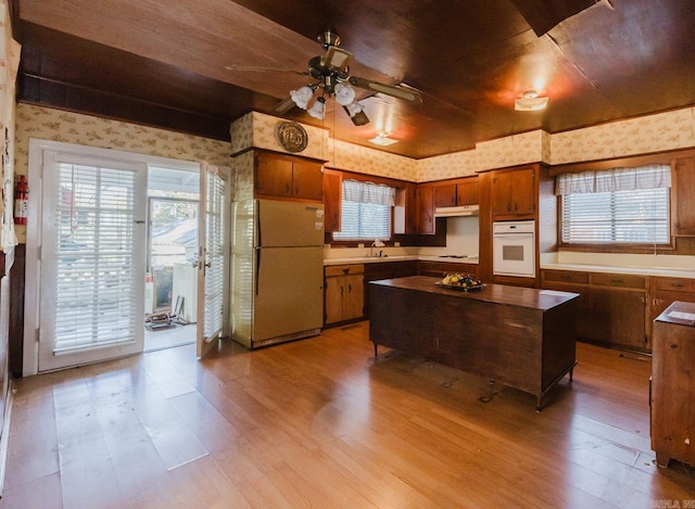 kitchen featuring ceiling fan, sink, light hardwood / wood-style floors, and white appliances