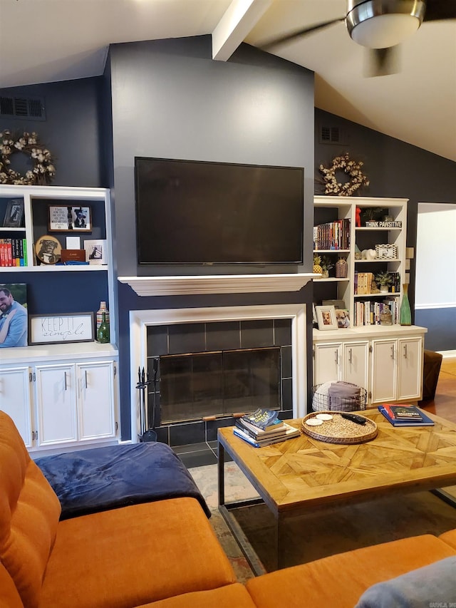 living room featuring a tile fireplace, lofted ceiling with beams, and hardwood / wood-style flooring