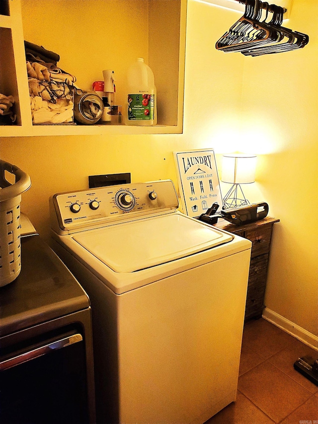 clothes washing area featuring washing machine and dryer and dark tile patterned flooring