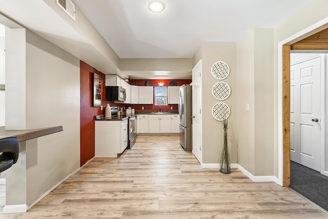 kitchen with white cabinetry, sink, stainless steel appliances, and light wood-type flooring