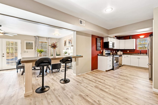 kitchen with white cabinets, sink, light hardwood / wood-style flooring, ceiling fan, and stainless steel appliances