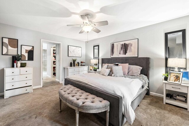 bedroom with a closet, a walk in closet, light colored carpet, and ceiling fan