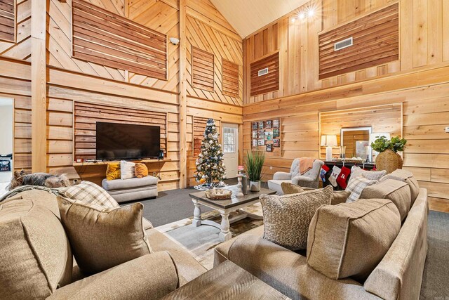 carpeted living room with wooden walls, high vaulted ceiling, and wooden ceiling