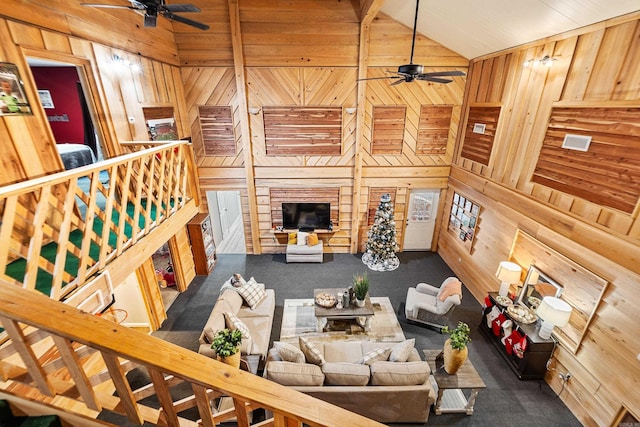 living room with high vaulted ceiling, ceiling fan, and wooden walls