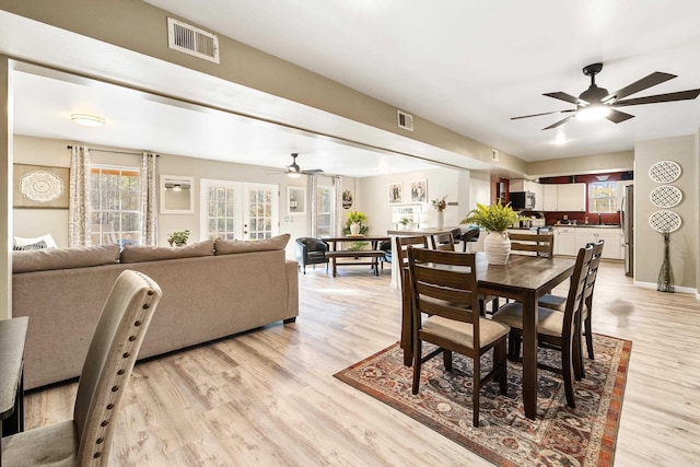 dining area with french doors, light wood-type flooring, ceiling fan, and sink