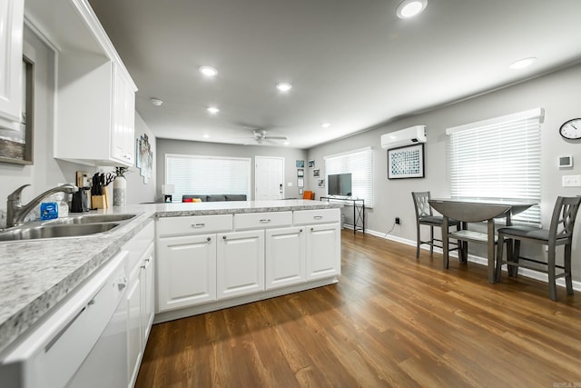 kitchen with kitchen peninsula, a wall unit AC, sink, dishwasher, and white cabinetry