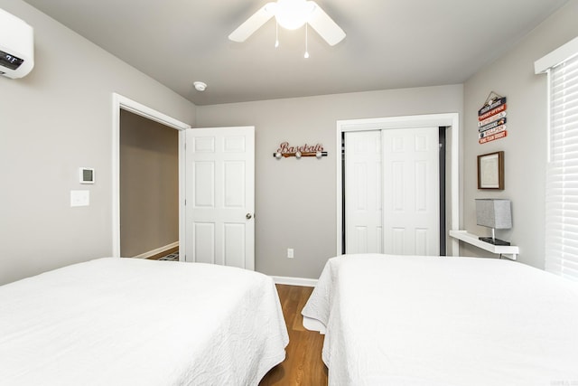 bedroom featuring a wall mounted air conditioner, dark hardwood / wood-style flooring, a closet, and ceiling fan