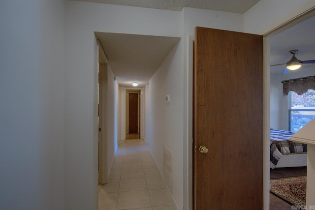 corridor featuring light tile patterned floors and a textured ceiling