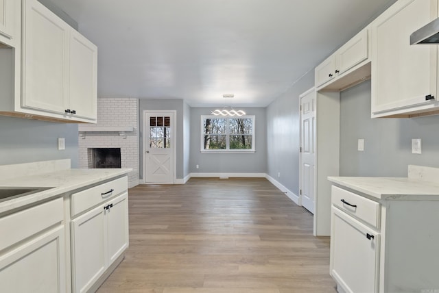 kitchen featuring white cabinetry, a fireplace, light hardwood / wood-style floors, and decorative light fixtures