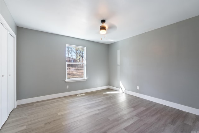 unfurnished bedroom featuring a closet, light hardwood / wood-style flooring, and ceiling fan