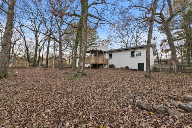 rear view of property with central AC unit, a storage unit, and a deck