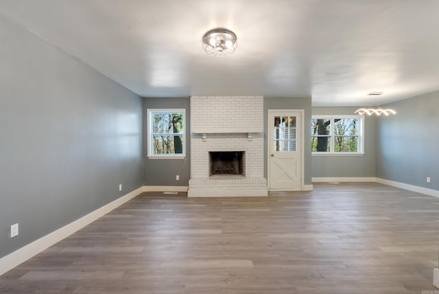 unfurnished living room with hardwood / wood-style floors, a brick fireplace, and a wealth of natural light