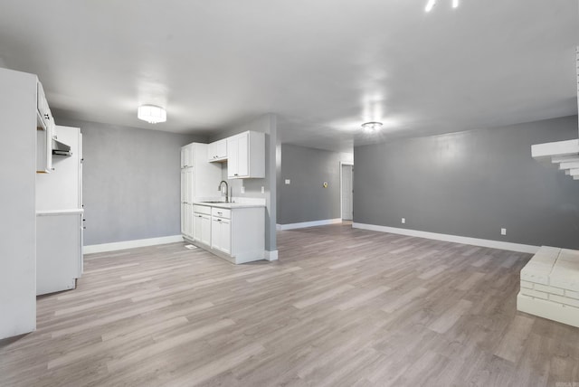 kitchen with white cabinets, light hardwood / wood-style floors, and sink