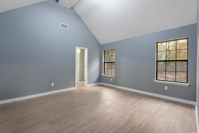 spare room featuring light wood-type flooring and high vaulted ceiling