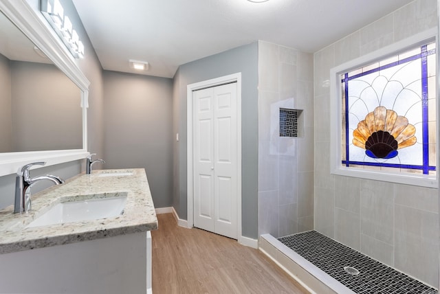 bathroom with a tile shower, vanity, hardwood / wood-style flooring, and a wealth of natural light