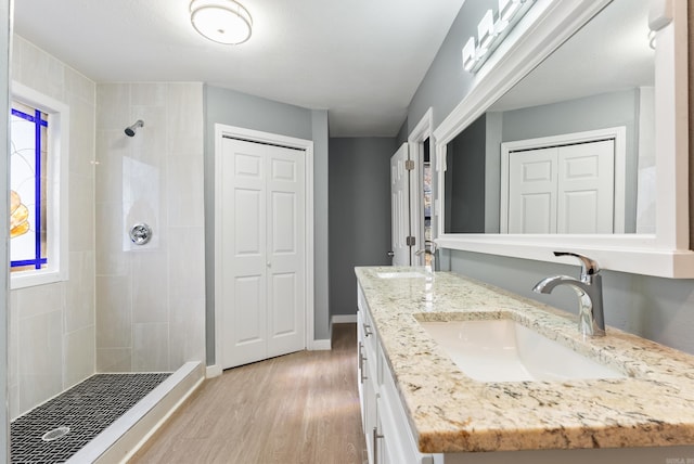 bathroom featuring a tile shower, vanity, and wood-type flooring