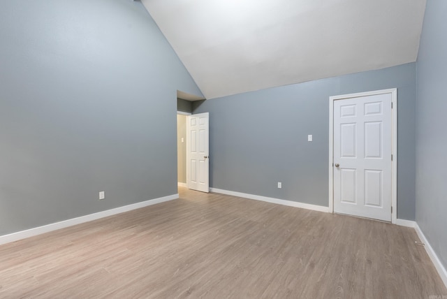 empty room with light hardwood / wood-style floors and high vaulted ceiling