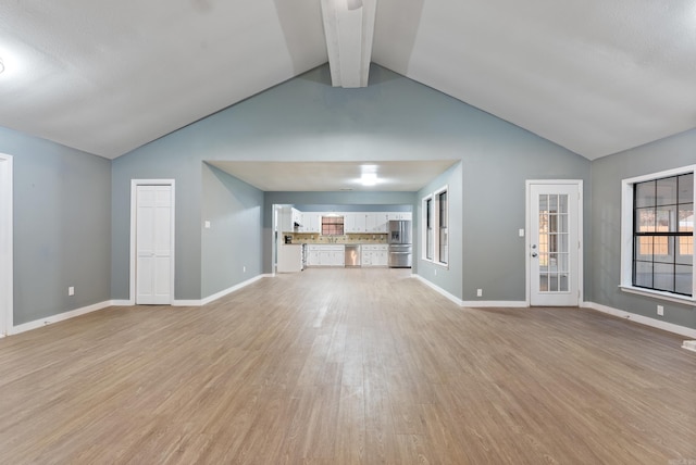 unfurnished living room with vaulted ceiling with beams and light hardwood / wood-style flooring