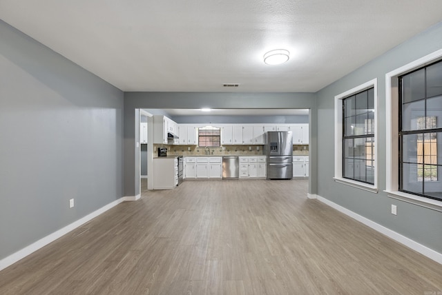 unfurnished living room featuring sink, light wood-type flooring, and a textured ceiling