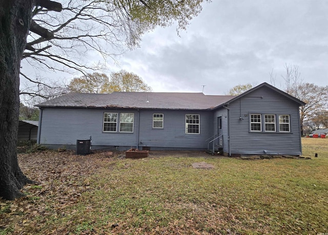 back of property featuring central AC unit and a lawn