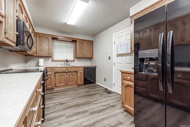 kitchen featuring sink, black appliances, a textured ceiling, and light hardwood / wood-style floors