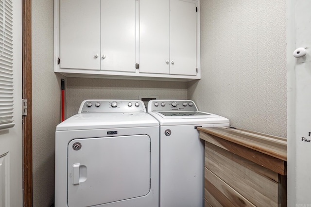 clothes washing area with washer and dryer and cabinets