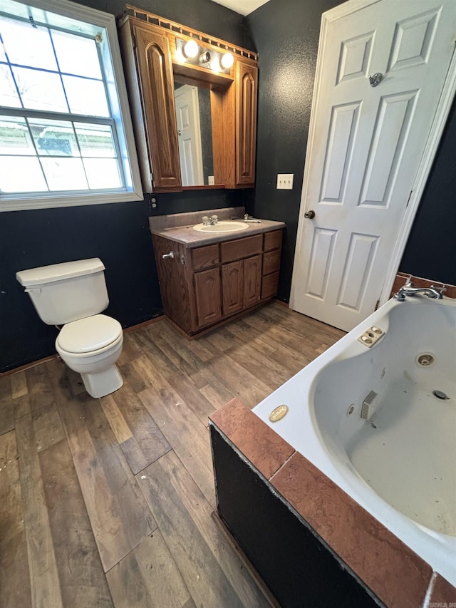 bathroom with toilet, hardwood / wood-style floors, vanity, and a washtub