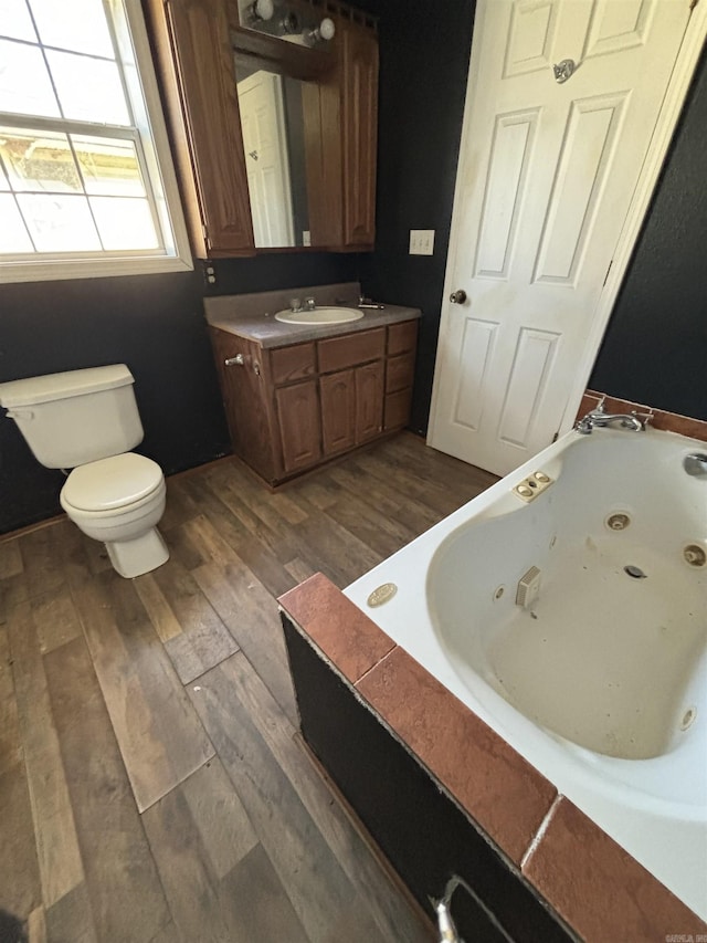 bathroom with a washtub, wood-type flooring, vanity, and toilet