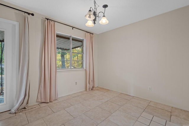 empty room with light tile patterned floors and a chandelier