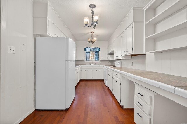kitchen with white appliances, hanging light fixtures, tile counters, white cabinetry, and a chandelier